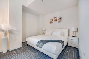 A hotel room with a large bed, two bedside tables, a vase with white flowers, and abstract wall art. - Downtown Chicago Stay with Free In & Out Parking 6 (Chicago)