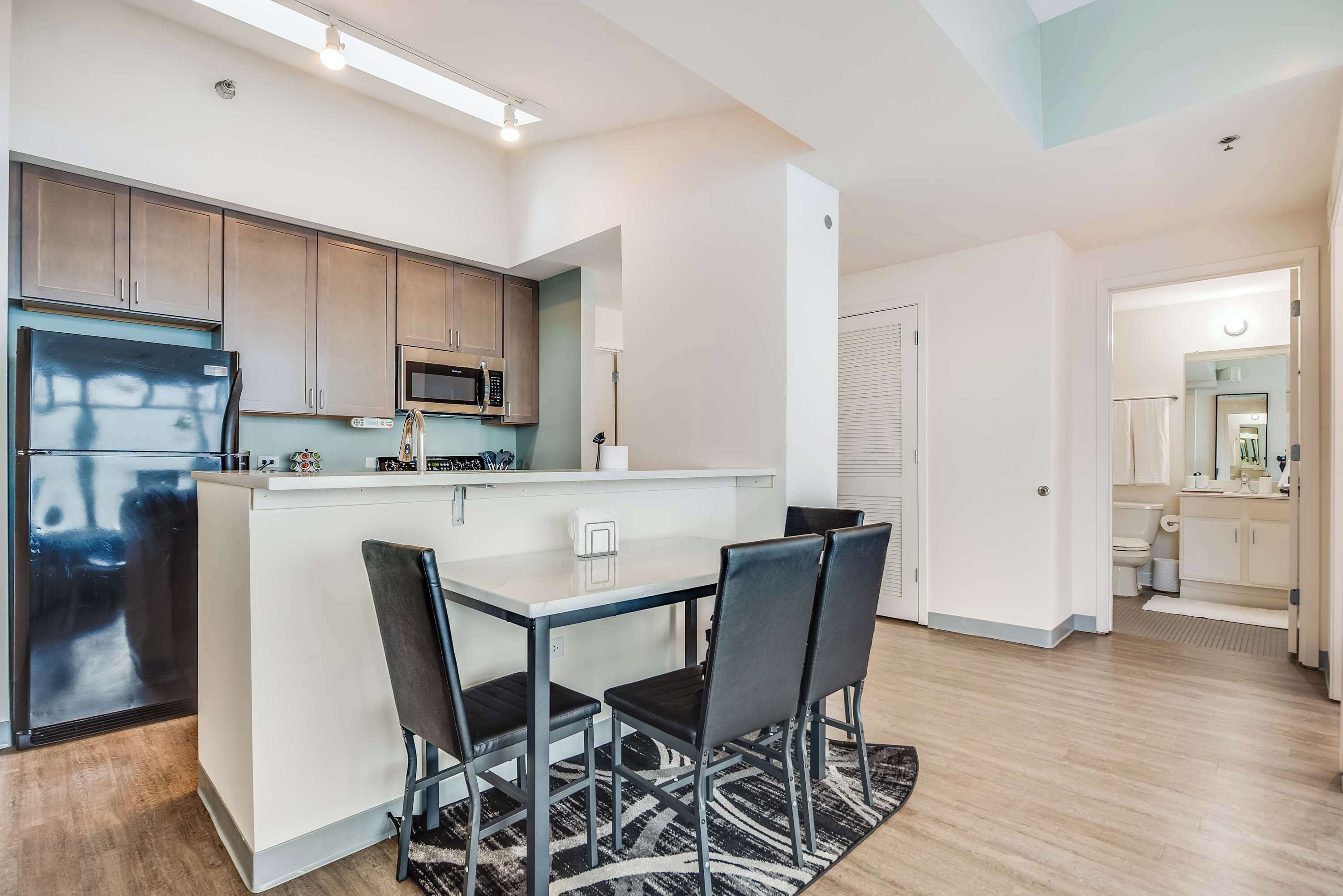 A modern kitchen with a central island, built-in appliances, and a dining area with chairs.