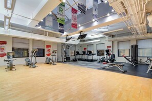 Un gimnasio con equipo de ejercicio diverso, pancartas y suelo de madera.