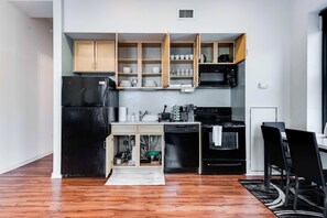 A compact kitchen with wooden cabinets, a black refrigerator, a microwave, and a dishwasher. - Downtown Chicago Stay with Free In & Out Parking 4 (Chicago)