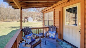 Eine hölzerne Veranda mit zwei Adirondack-Stühlen und einem kleinen Tisch.