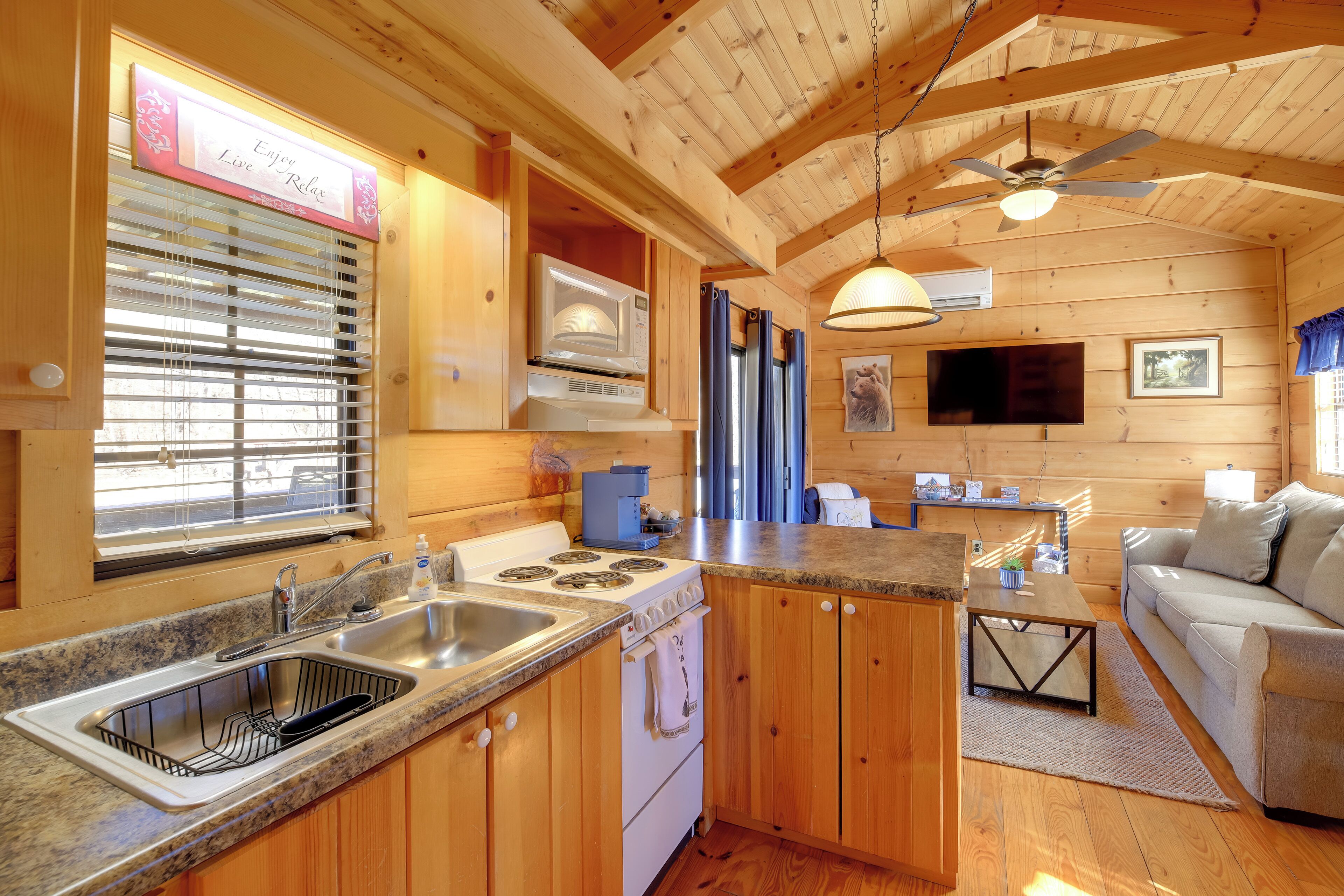 A wooden cabin interior with a kitchen, dining area, and a living room.