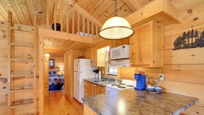 Ein Holzblockhaus-Innenraum mit Küchenzeile, darunter ein Herd, eine Mikrowelle und Holzschränke.
