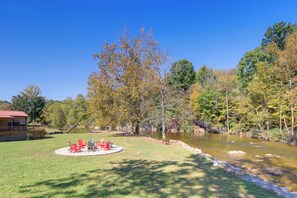 A riverside property with a deck and outdoor seating area. - Bike, Hike, Ride & Fish from Cozy Creekside Cabin (Damascus)