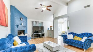 Un salon spacieux avec un canapé bleu, une table basse blanche et une cheminée.