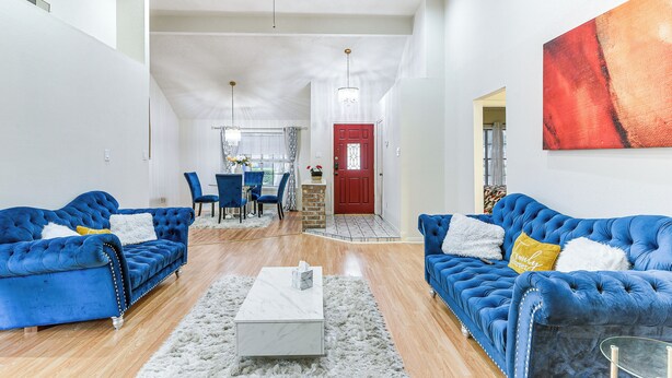 Un salon spacieux avec deux canapés bleus, une table basse blanche et une porte rouge en arrière-plan.