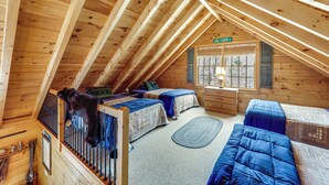 A cabin with two beds, a wooden ceiling, a window with shutters, and a sign reading "LOG CABIN." - Game Room, Deck! Cozy Ski Cabin Near Sugarloaf (Eustis)