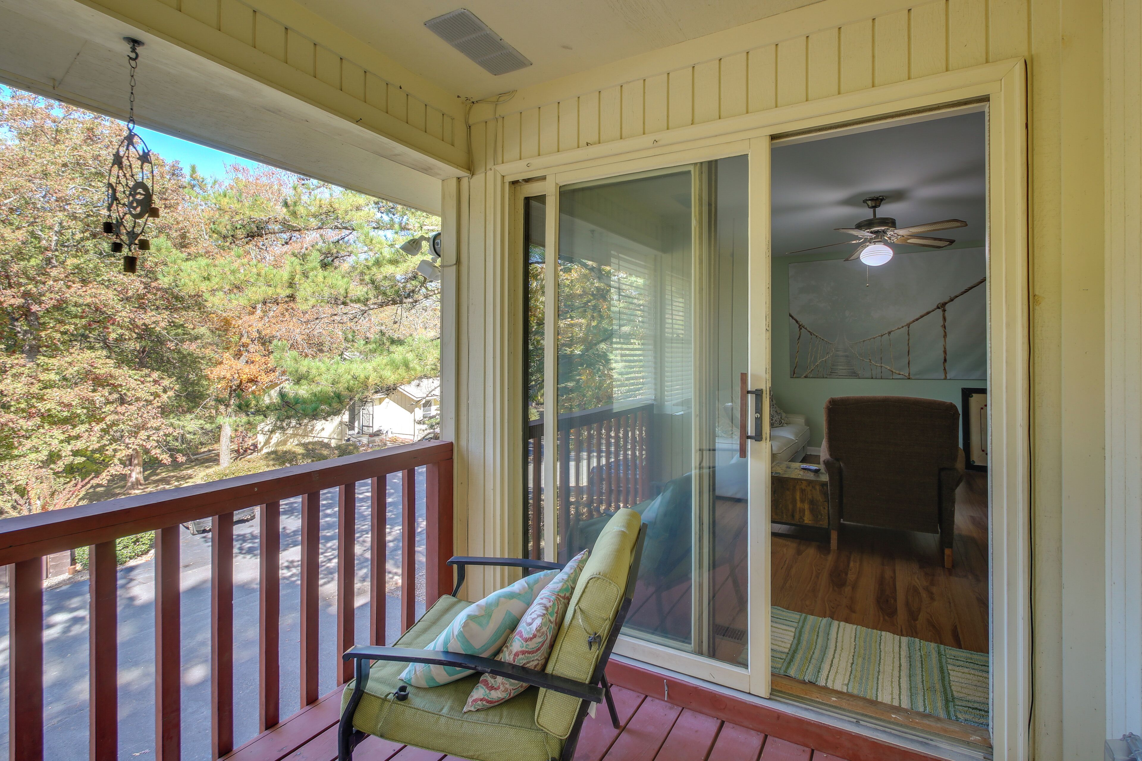 A balcony with a chair and a view of a forest.