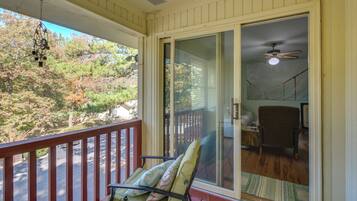 A balcony with a chair and a view of a forest.