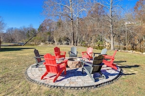 Ein kreisförmiger Außenbereich mit Sitzgelegenheiten, einem Feuerkorb und Adirondack-Stühlen.