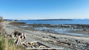 A rocky beach with a clear view of the ocean and distant mountains. - The Grove Guest House (Campbell River)