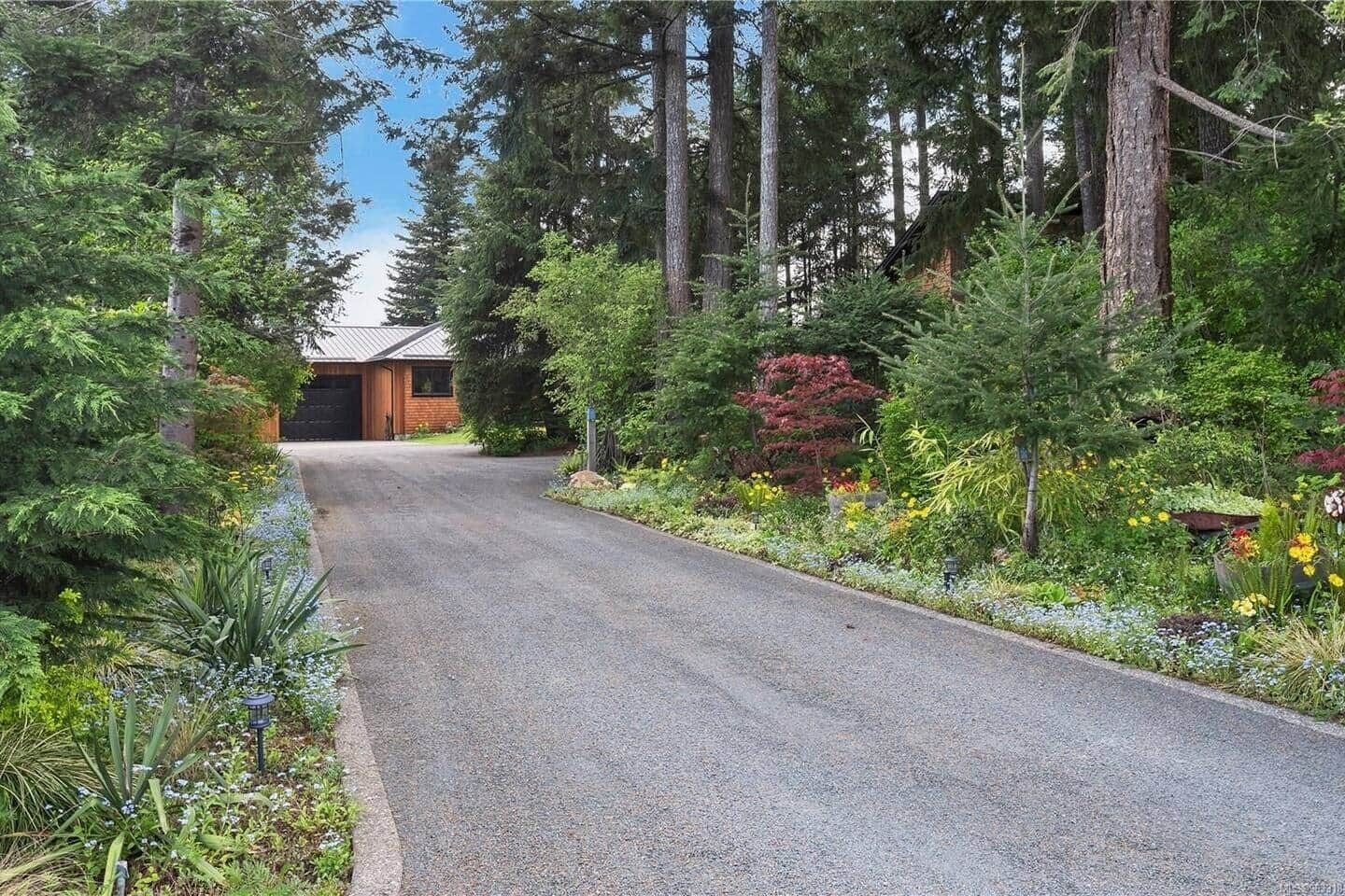 A residential property with a paved driveway leading to a wooden house.