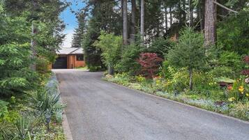 A residential property with a paved driveway leading to a wooden house.