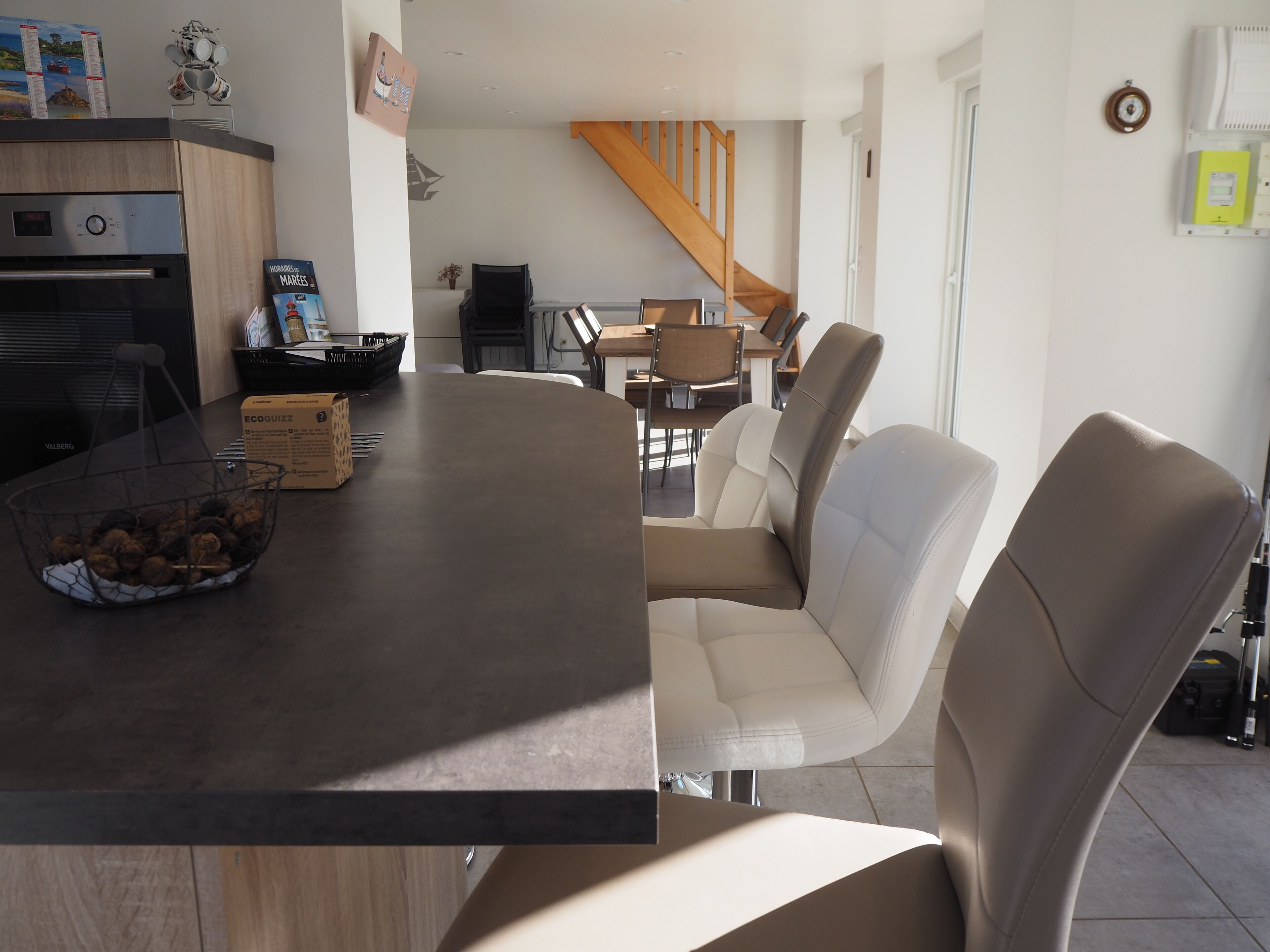 A modern kitchen with a dark countertop, a bowl of snacks, and a coffee machine.
