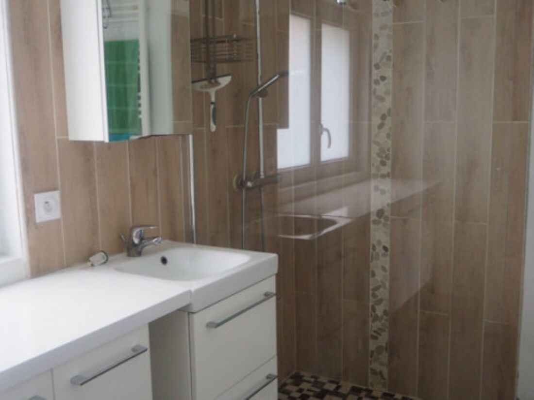 A bathroom with a white sink, a mirror, and a shower area with a glass door.