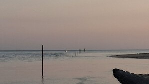 Ein Strand mit ruhigem Wasser, einigen Pfählen und einem entfernten Boot.