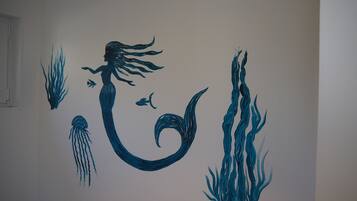 Una pared con una ilustración de sirena y decoración temática marina.