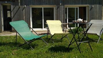 Un edificio in legno con un patio arredato con tre sedie e un tavolo, su cui ci sono tazze e un teiera.