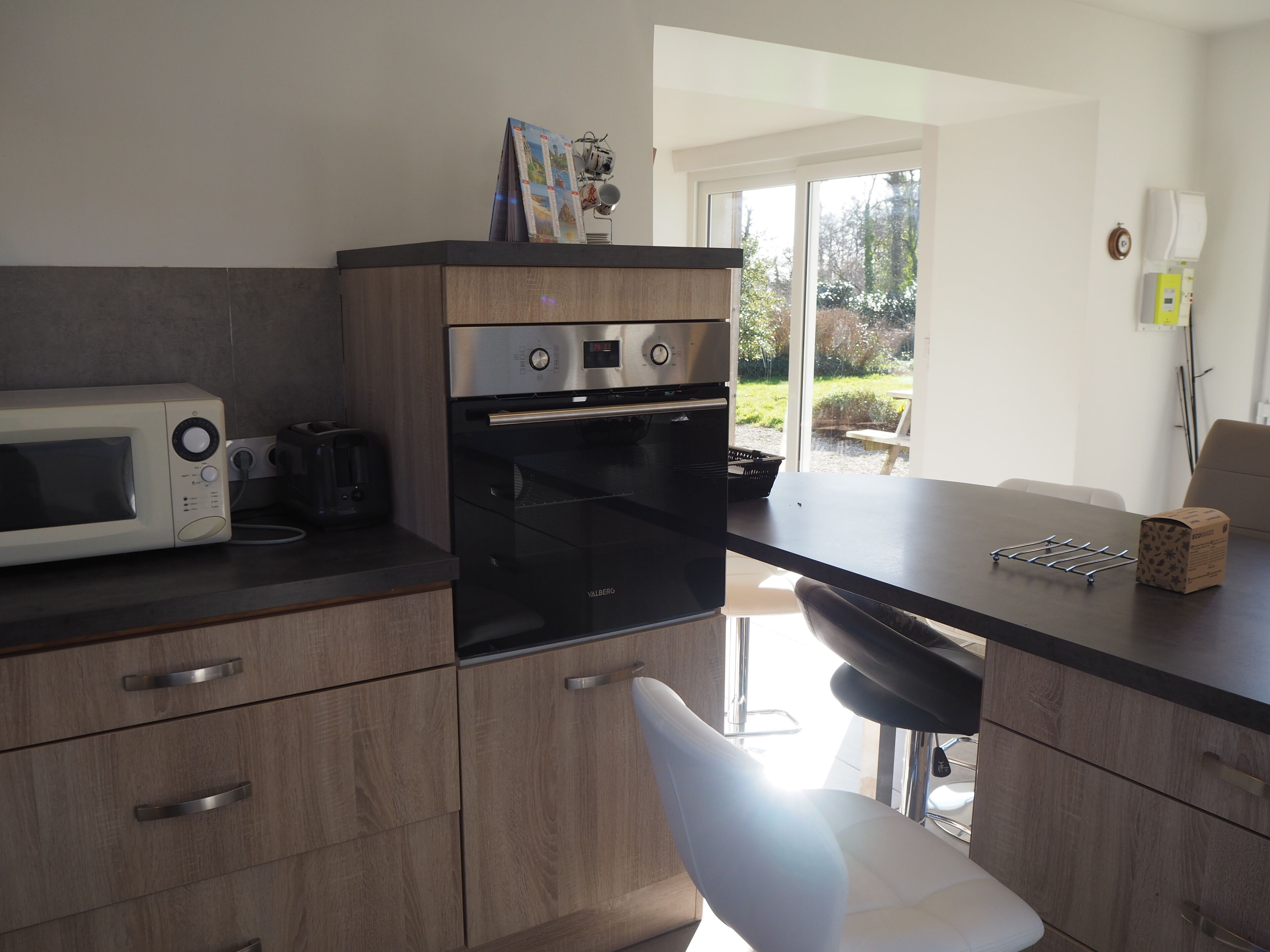 A modern kitchen with a microwave, toaster, and oven. There is a window providing a view of the outdoors.
