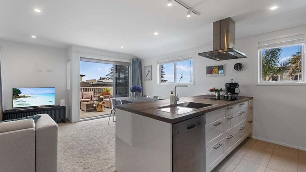 A modern kitchen with a central island, a built-in oven, and a large window. - Endless Summer Retreat - Mt Maunganui (Mount Maunganui)