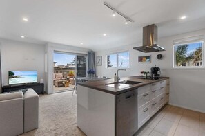 A modern kitchen with a central island, a built-in oven, and a large window. - Endless Summer Retreat - Mt Maunganui (Mount Maunganui)