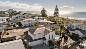 A residential area with houses, a swimming pool, and a beach in the background. - Endless Summer Retreat - Mt Maunganui (Mount Maunganui)
