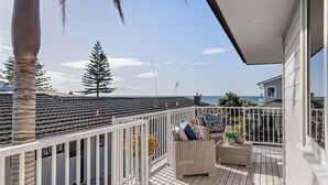 A balcony with a view of the ocean, a white railing, and outdoor furniture. - Endless Summer Retreat - Mt Maunganui (Mount Maunganui)