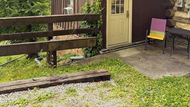 Una cabaña rústica con fachada de madera, una puerta principal y un pequeño porche.