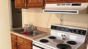 Una cocina con armarios de madera, una estufa blanca y un fregadero.
