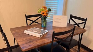 A wooden table with four black chairs, a vase with flowers, and a fire exit sign on the wall. - The Barn at Wendover - 4 BR 2 BA (Wendover)
