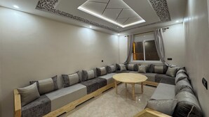 A modern living room with a large L-shaped sectional sofa, a round coffee table, and a skylight ceiling. - Fantastic 3-bedroom apartment in cool Oujda for your stay (Oujda)