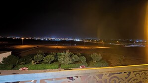 A nighttime view from a balcony overlooking a cityscape with illuminated buildings in the distance. - Fantastic 3-bedroom apartment in cool Oujda for your stay (Oujda)
