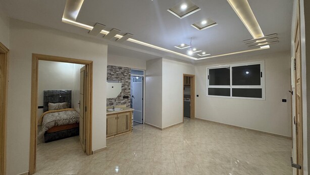 A spacious room with a bed, a vanity with a mirror, and a window. - Fantastic 3-bedroom apartment in cool Oujda for your stay (Oujda)