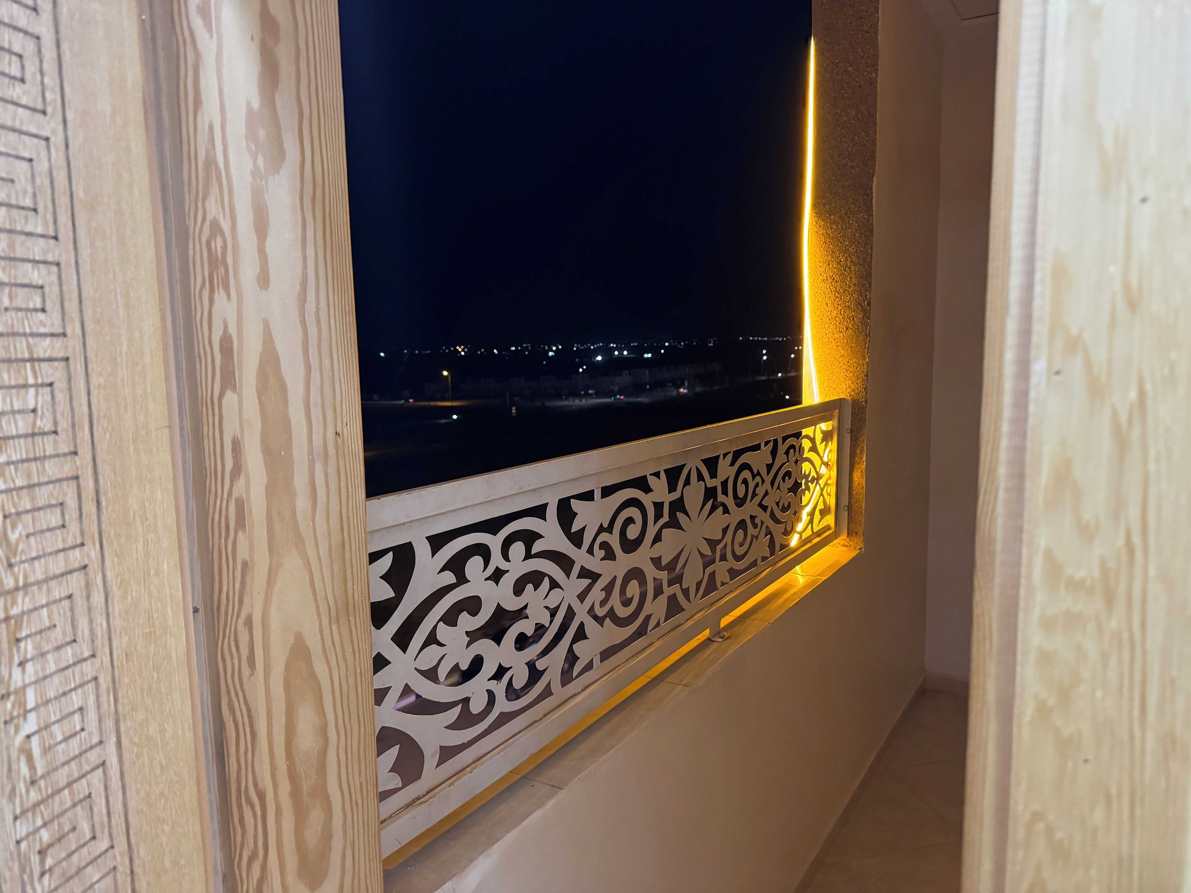 A balcony with a decorative railing and a view of a cityscape at night.