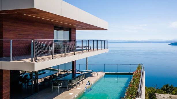 Ein modernes Gebäude mit Pool mit Blick auf ein Gewässer.