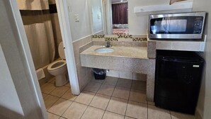 Een kleine badkamer met toilet, wastafel en een magnetron.