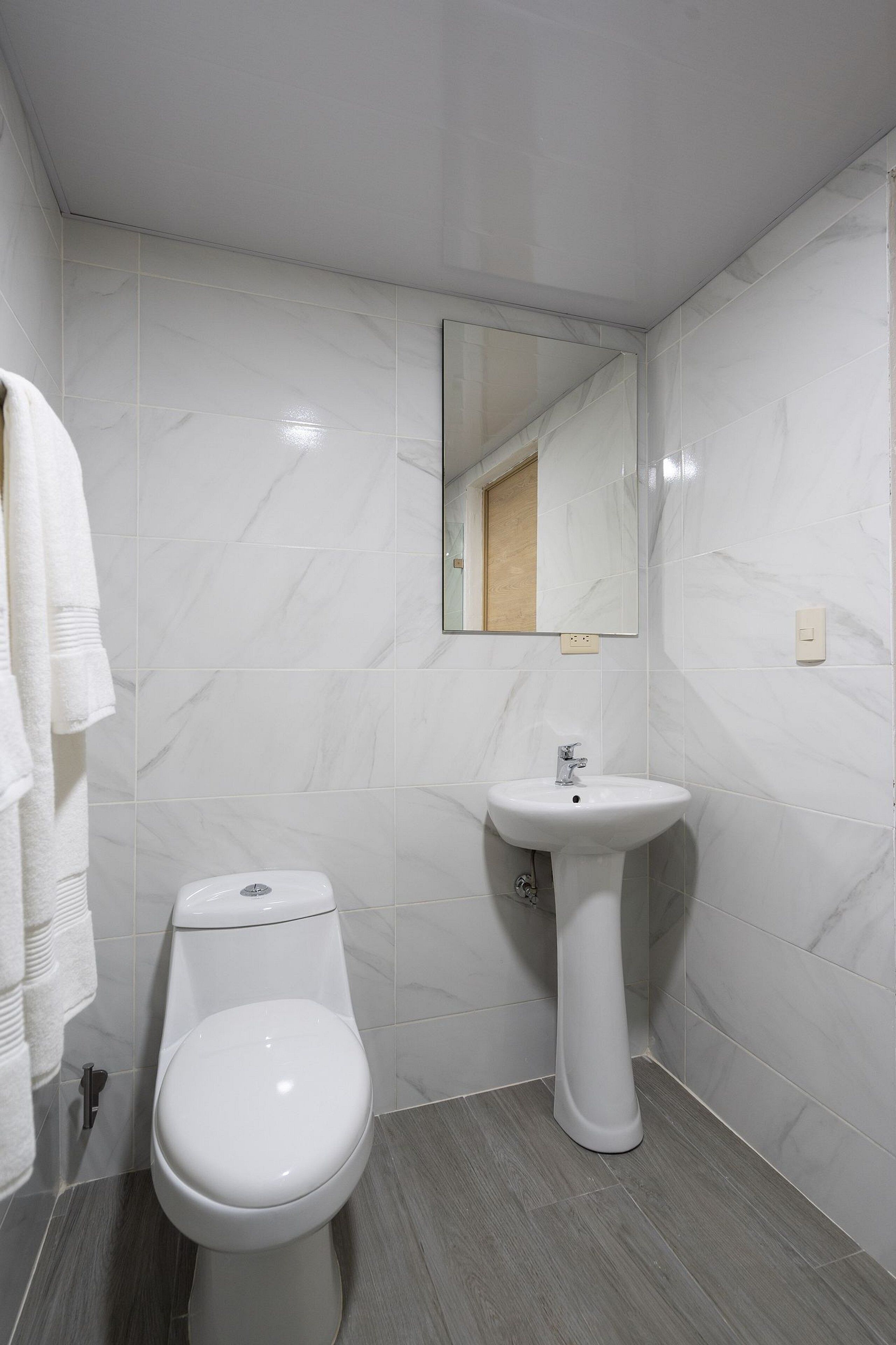 Un baño con inodoro, lavamanos y espejo.