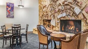 A cozy room with a stone fireplace, a dining table with chairs, and a poster on the wall. - 2 bedroom unit, sleeps 6 for Christmas week across Heavenly Valley Ski Resort (South Lake Tahoe)