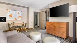 A hotel room with a flat-screen TV, a wooden dresser, a dining area with a table and chairs, and a large painting on the wall. - 2 bedroom unit, sleeps 6 for Christmas week across Heavenly Valley Ski Resort (South Lake Tahoe)