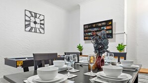 Un comedor con mesa de billar, un reloj y una pared decorada con cuadros.