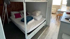 Ein Schlafzimmer mit Etagenbetten, einer Holzleiter, einem Schreibtisch und einem Stuhl.