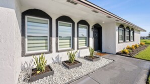 A modern building with a covered porch, large windows, and outdoor planters. - Golf & Beach Retreat Firepit BBQ Near Boca Grande (Rotonda West)
