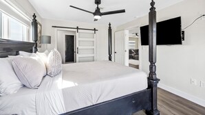 A bedroom with a four-poster bed, a ceiling fan, a flat-screen TV mounted on the wall, and a sliding door closet. - Golf & Beach Retreat Firepit BBQ Near Boca Grande (Rotonda West)