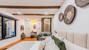 Une chambre avec un grand lit, un bureau et une chaise. Deux grands paniers en osier sont accrochés au mur.