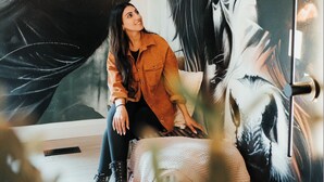 Une personne est assise dans une pièce dont un mur est orné d’une grande fresque abstraite.