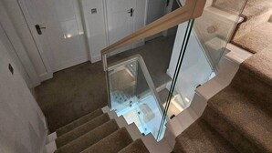 A staircase with glass railings and carpeted steps. - The Minimalist's Retreat Oxford (Oxford)
