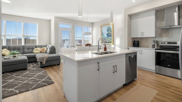 Una cocina moderna con una isla central, muebles de cocina blancos y electrodomésticos de acero inoxidable.