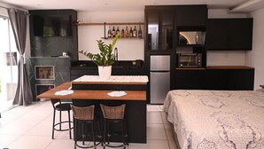 Cozinha moderna com ilha central, armários pretos e área de refeições com duas cadeiras de vime.