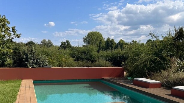 A rectangular swimming pool with a wooden deck and red planters. - Bed and breakfast, with private bathroom, 6kms from Montauban. (Montauban)