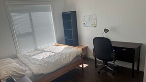 A bedroom with a bed, a desk, a chair, and a map on the wall. - 5 min walk to university with stunning mountain views (Kelowna)
